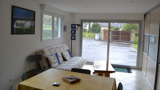 A room with a sofa, a table, and a window. - RENTAL CONCARNEAU LE CABELLOU 80 M FROM THE BEACH (Concarneau)