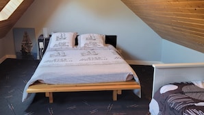 A bedroom with a sloped ceiling, a bed with a white bedspread, and a small ship decoration on the wall. - RENTAL CONCARNEAU LE CABELLOU 80 M FROM THE BEACH (Concarneau)