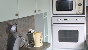 A kitchen with a microwave, oven, and coffee maker on a countertop. - RENTAL CONCARNEAU LE CABELLOU 80 M FROM THE BEACH (Concarneau)