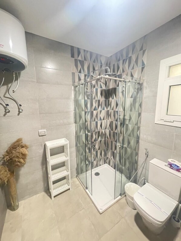 A bathroom with a shower, toilet, and a towel rack.