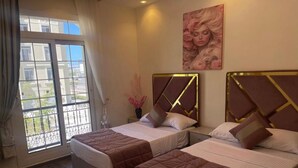 Une chambre d’hôtel avec deux lits, une grande fenêtre donnant sur un beau paysage et un tableau accroché au mur.