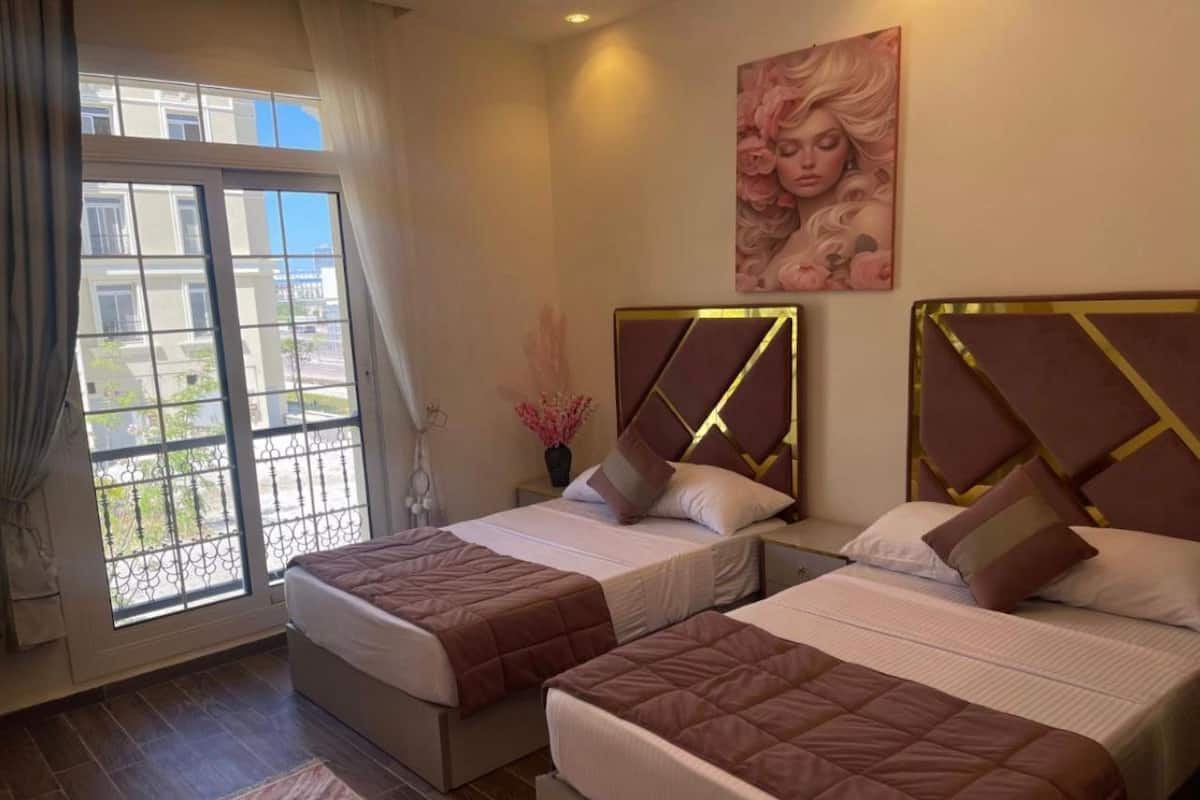 Une chambre d’hôtel avec deux lits, une grande fenêtre donnant sur un beau paysage et un tableau accroché au mur.
