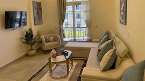 Un salon moderne avec un canapé, un fauteuil et un téléviseur fixé au mur.