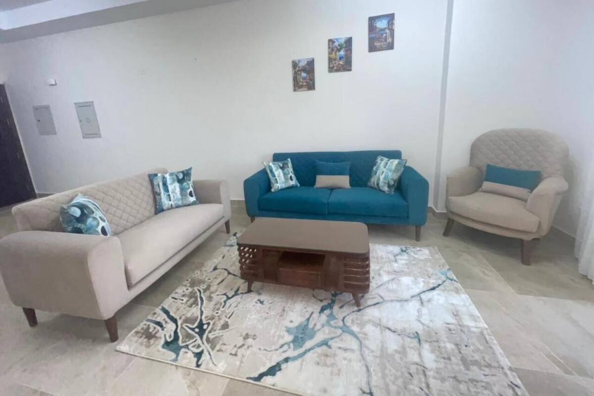 Un salon avec un canapé beige, un canapé bleu, une table basse en bois et un tapis à motifs.