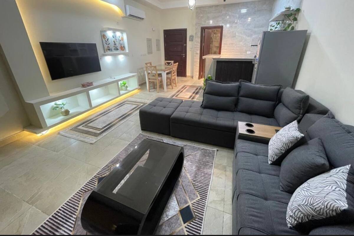 Un salon moderne avec un canapé d’angle, un téléviseur à écran plat et un coin repas.