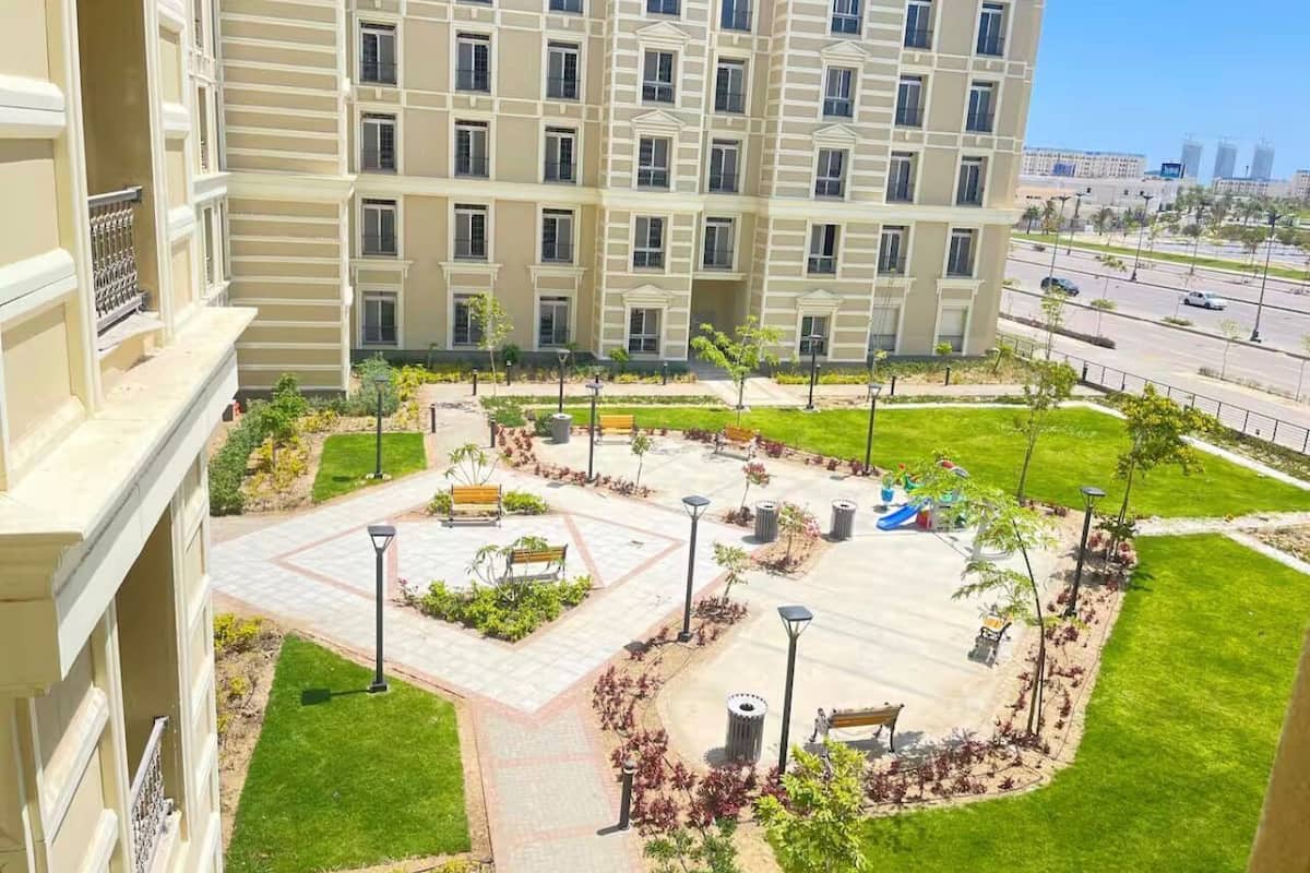 Un hôtel à plusieurs étages doté d’une cour intérieure comprenant une aire de jeux, des bancs et des espaces paysagers.