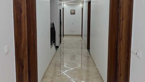A hallway with wooden doors, a marble floor, and recessed lighting. - Hotel Vinayak -Banganga Road Katra  (Reasi)