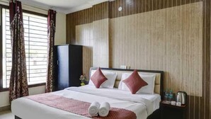 A hotel room with a large bed, a ceiling fan, a wardrobe, and a window with curtains. - Hotel Vinayak -Banganga Road Katra  (Reasi)