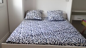 A single-bed room with a patterned bedspread, white walls, and a small window. - Quiet T1 in St Marc sur Mer, 5 min walk to the beach, terrace and large bed! (Saint-Nazaire)