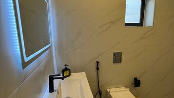 A modern bathroom with a white sink, mirror, and toilet.