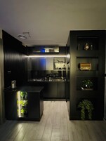 Una cocina moderna con una isla central, electrodomésticos integrados y objetos decorativos en estantes.