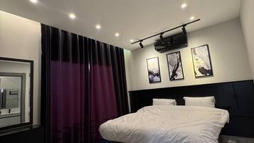 A modern bedroom with a large bed, dark headboard, and a ceiling projector.