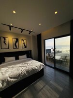 Un dormitorio moderno con una cama grande, vistas al exterior a través de una puerta corrediza de vidrio y tres obras de arte abstracto en la pared.