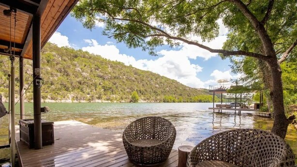 A wooden deck with wicker chairs overlooking a lake and hills. - Lake Austin Luxury/200ft Private Waterfront on 2 Acres/2 Docks/Sleeps 4 (Austin)