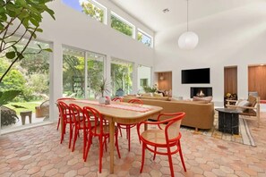 Una sala de estar amplia con un sofá grande, un comedor con sillas rojas y una chimenea.