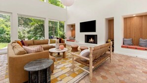 A spacious living room with a fireplace, large windows, and a view of greenery. - Lake Austin Luxury/200ft Private Waterfront on 2 Acres/2 Docks/Sleeps 4 (Austin)