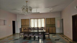 A spacious room with a dining table and chairs, a chandelier, and a patterned floor.