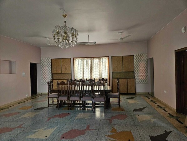 Una habitación amplia con una mesa de comedor y sillas, un candelabro y un suelo con diseño.