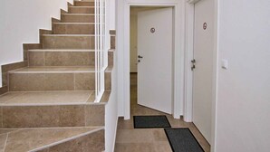 Un escalier recouvert de carreaux de couleur beige mène à une porte ornée d’un logo circulaire.