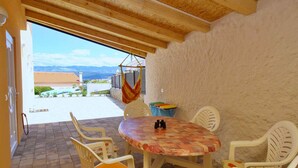Une terrasse couverte avec une table et des chaises, un hamac et une vue sur un paysage montagneux.