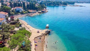 Vue aérienne d’une ville côtière avec une plage, une eau d’un bleu limpide et une jetée.