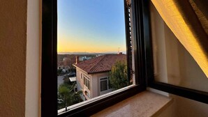 Janela com vista para uma área residencial, incluindo casas e céu claro.