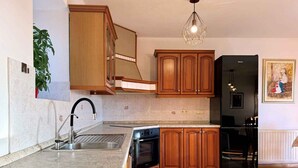 Uma cozinha moderna com armários de madeira, uma geladeira preta, forno embutido e bancada de granito.