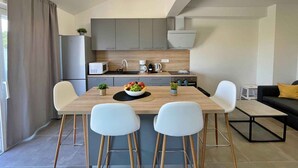 Eine moderne Küche mit grauen Schränken, einer Holzausziehtafel und einem Essbereich mit zwei weißen Stühlen und einem Tisch.