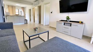 A modern living room with a grey sofa, a small table, and a TV mounted on the wall. - Holiday apartment, modernly furnished, with air conditioning (Šilo)