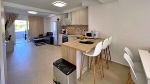 A modern kitchen with a wooden countertop, white bar stools, a microwave, and a sink. - Holiday apartment, modernly furnished, with air conditioning (Šilo)