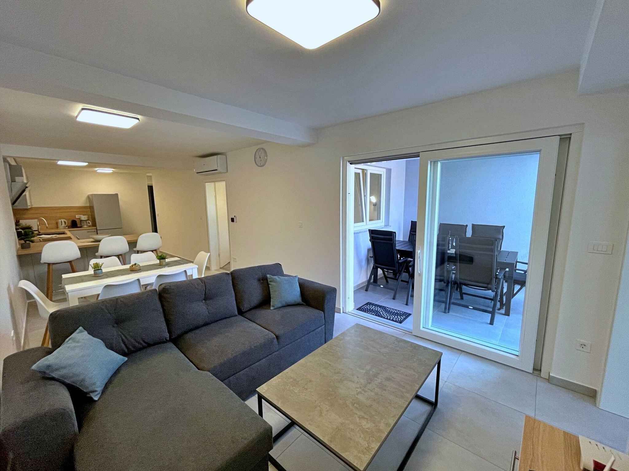 A modern living room with a sofa, a coffee table, and a dining area with chairs and a table.