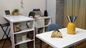 A modern, well-lit room with a white desk, a chair, a bookshelf, a small plant, and a yellow vase with pens. - Very large apartment in center the only one in Sicily with private cinema room. (Catania)