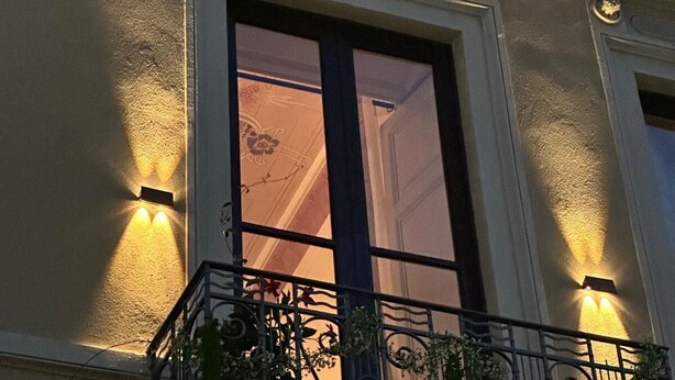 A building facade with a balcony, a large window, and wall-mounted lights. - Very large apartment in center the only one in Sicily with private cinema room. (Catania)