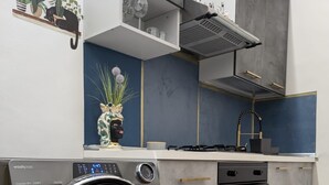 A modern kitchen with a built-in washer and dryer, grey cabinets, and a blue backsplash. - Very large apartment in center the only one in Sicily with private cinema room. (Catania)