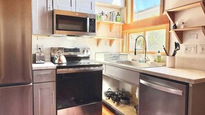 A modern kitchen with stainless steel appliances, wooden cabinets, and a window providing natural light.