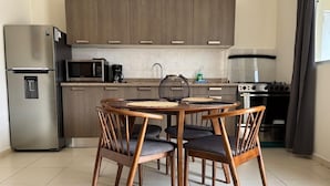 Una cocina moderna con armarios de madera, un refrigerador de acero inoxidable, un microondas, una cafetera y una estufa.