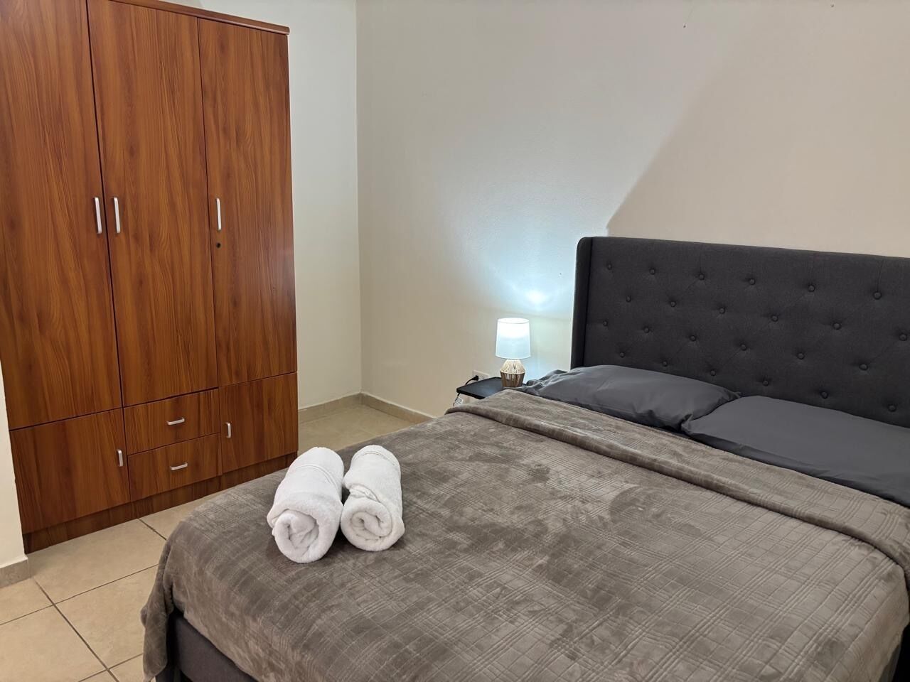 Une chambre à coucher avec un lit, une armoire et une table de chevet avec une lampe.