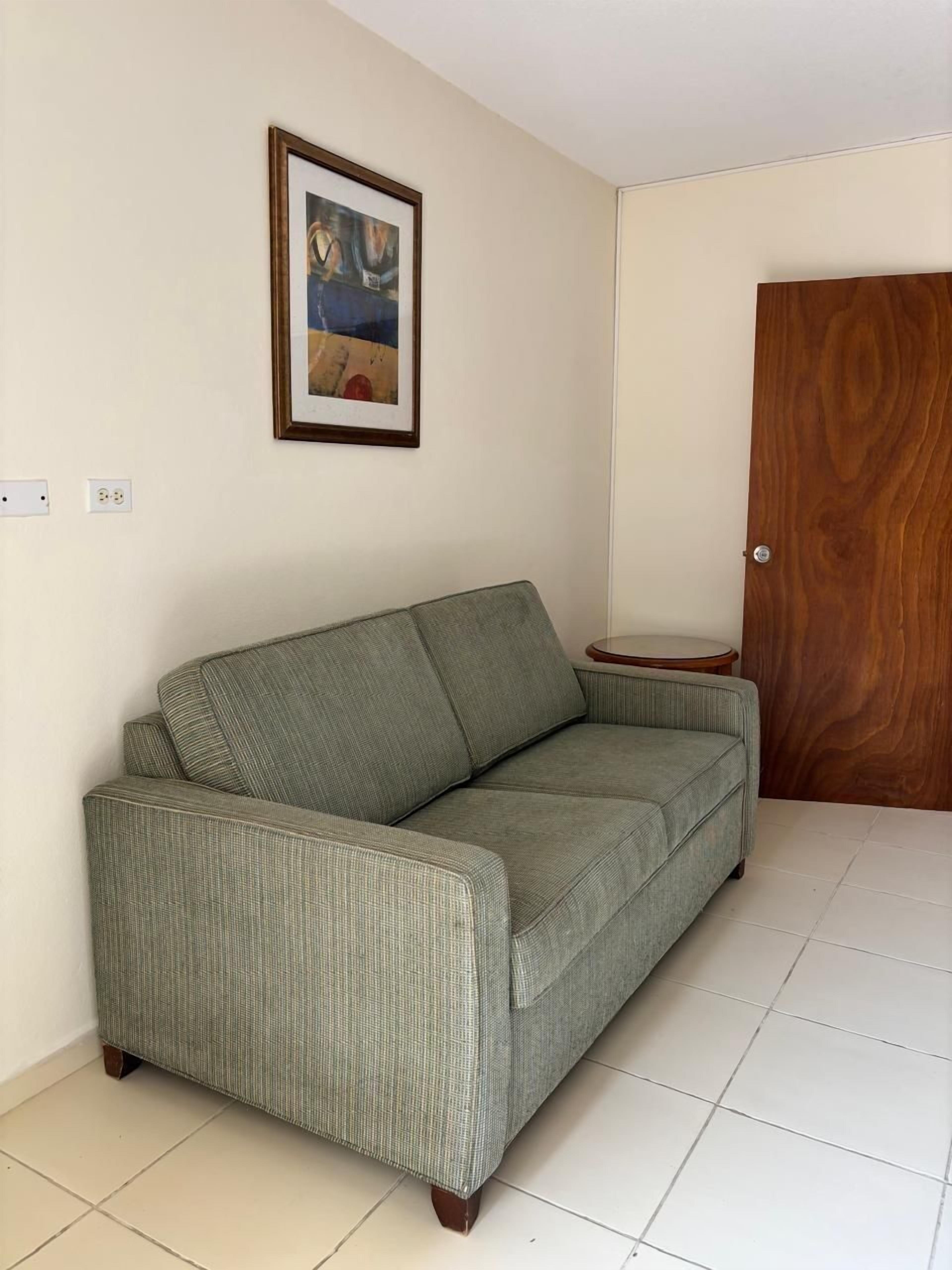 Ein grünes Sofa in einem Zimmer mit einer Holztür und einem gerahmten Bild an der Wand.