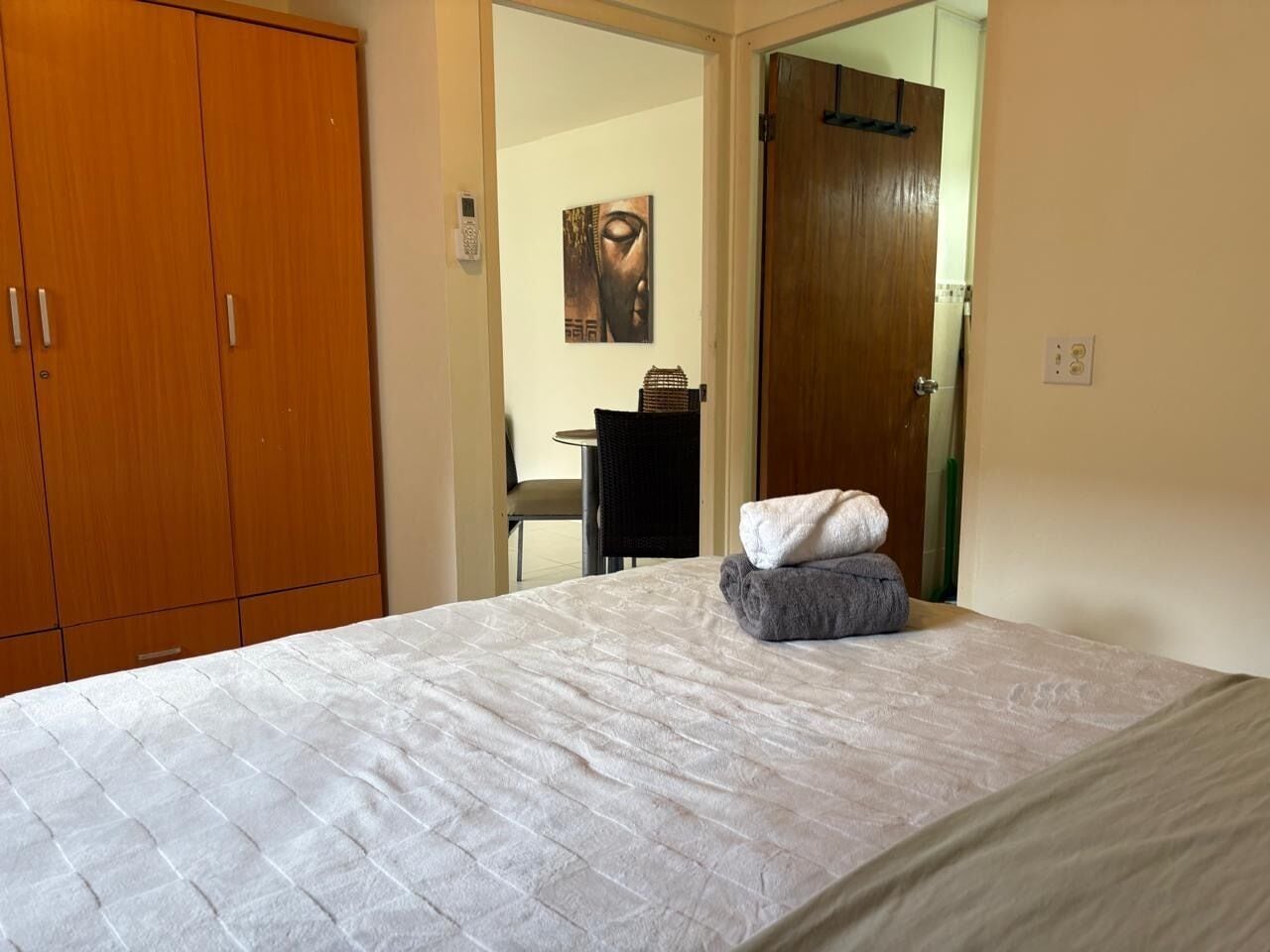 A bedroom with a bed, a wardrobe, a mirror, and a painting on the wall.