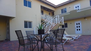 Un patio con mesa y sillas, una escalera y una zona de piscina.