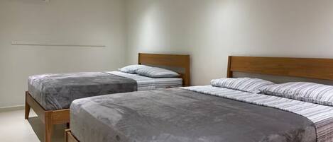 A bedroom with two beds, each with a wooden frame and grey bedding.