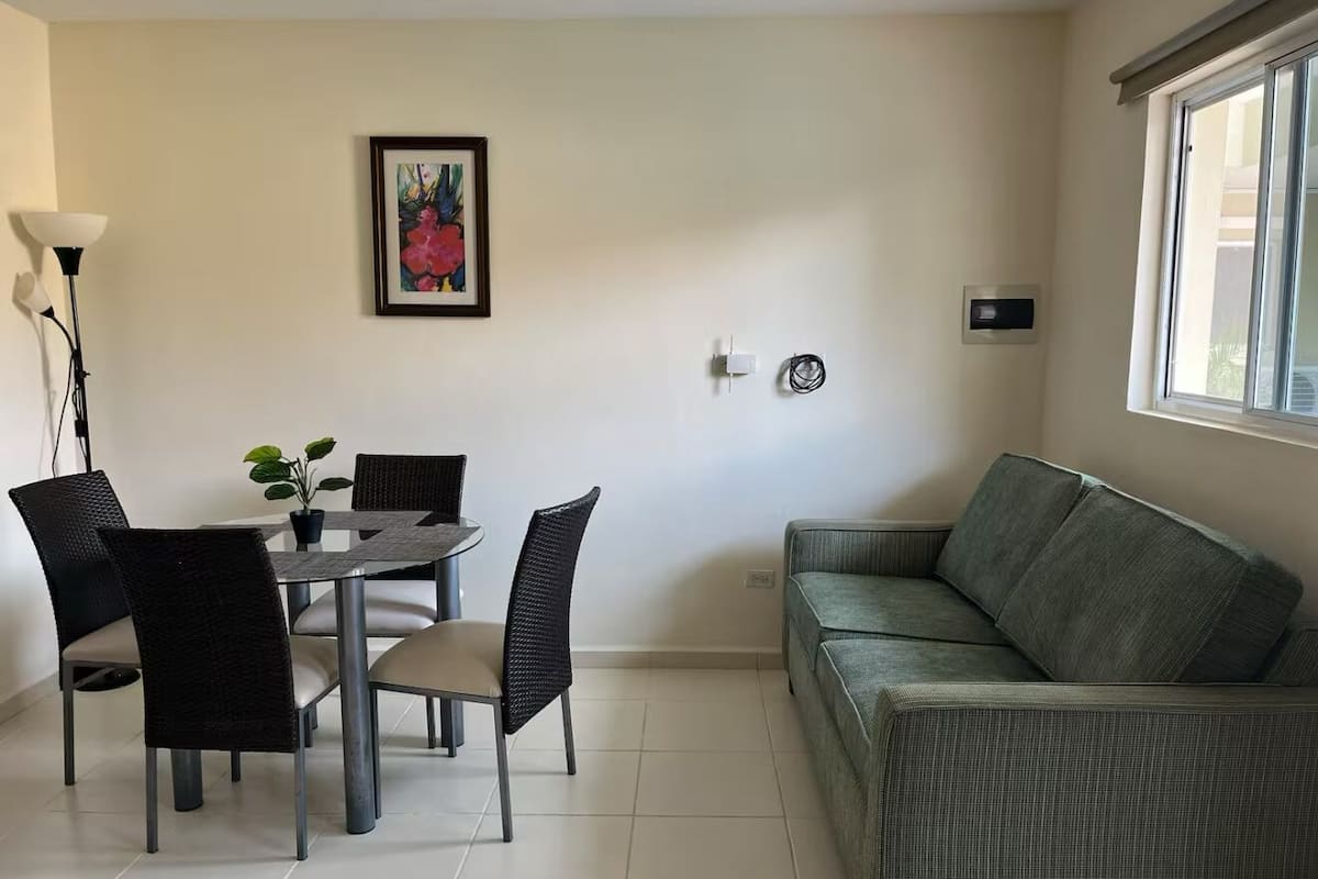 Una sala de estar moderna con comedor, un sofá y una obra de arte enmarcada en la pared.
