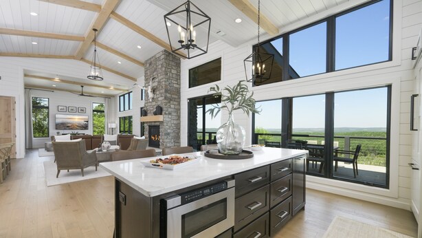 A spacious kitchen with a large island, built-in appliances, and a stone fireplace.
