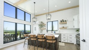 A modern kitchen with large windows, a bar area, and a view of the outdoors.