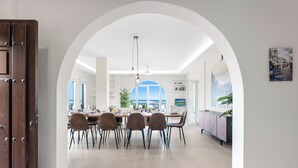 A modern dining area with a high arched doorway leading to a balcony with a view of the sea. - Belgravia Club Townhouse Estepona by Mabiente Properties (Estepona)
