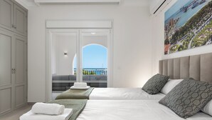 A hotel room with a bed, a sofa, a window with a view of the sea, and a painting on the wall. - Belgravia Club Townhouse Estepona by Mabiente Properties (Estepona)