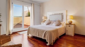 A bedroom with a bed, bedside lamps, a nightstand, a ceiling fan, and a view of the outside. - Casa Feliz Penthouse by Mabiente (Mijas)