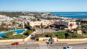 A coastal hotel with a swimming pool, a parking area, and a view of the sea and town. - Casa Feliz Penthouse by Mabiente (Mijas)