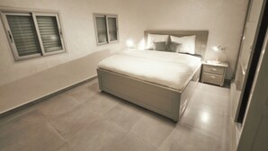 A modern bedroom with a large bed, bedside tables, and a wardrobe.