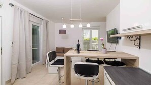 A modern kitchen with a dining area, featuring a wooden table, bar stools, and a TV mounted on the wall.